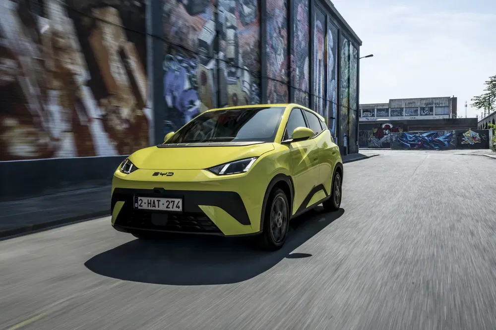 Gele BYD-auto rijdt in de stad, omringd door stedelijke graffiti.