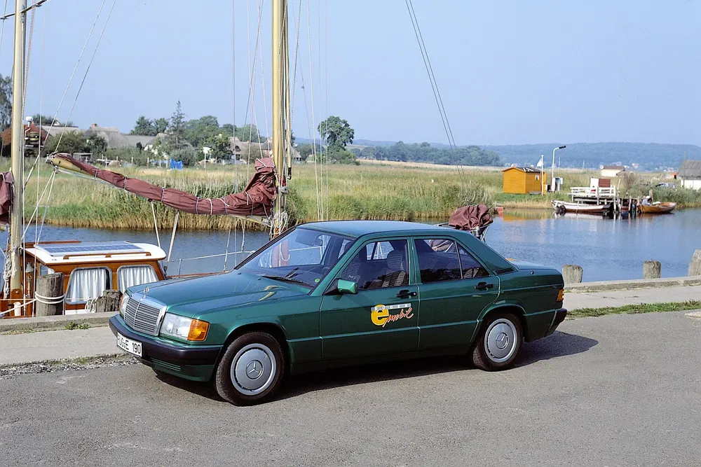 Voiture Mercedes-Benz verte stationnée près d'une rivière, modèle 190E électrique.
