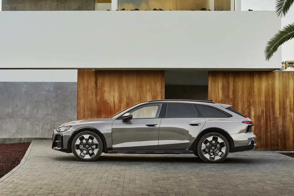 Grijze Audi A6 Avant e-tron geparkeerd voor een modern huis met minimalistisch ontwerp.