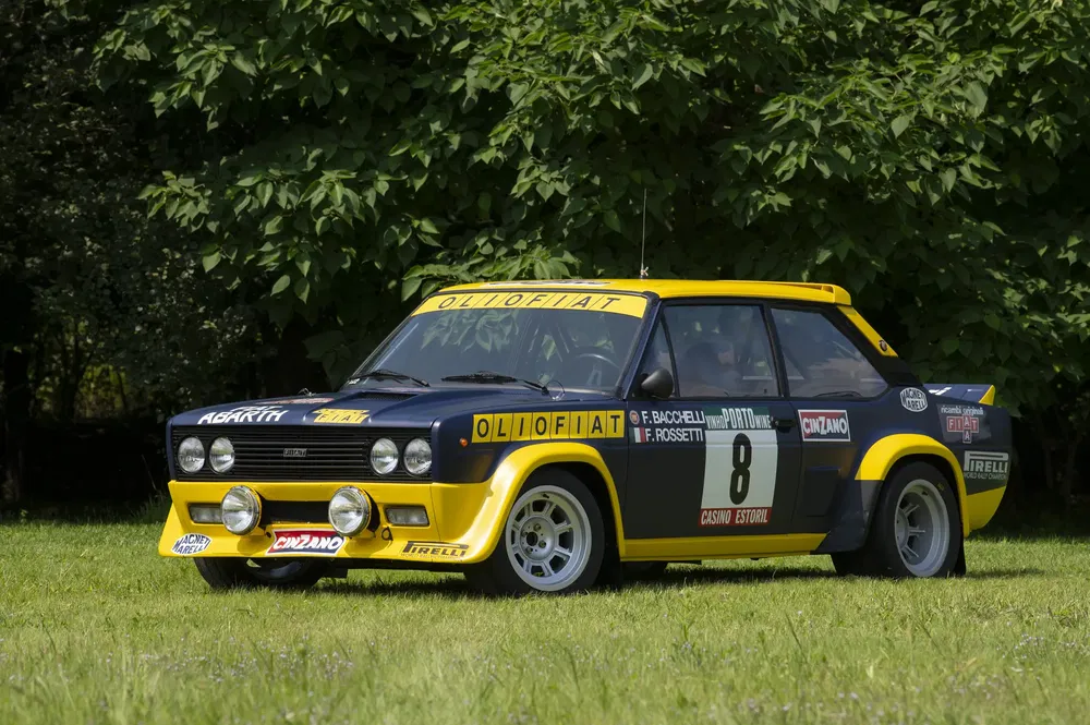 Fiat 131 Abarth met Olio Fiat livery, iconische raceauto op groen grasveld.