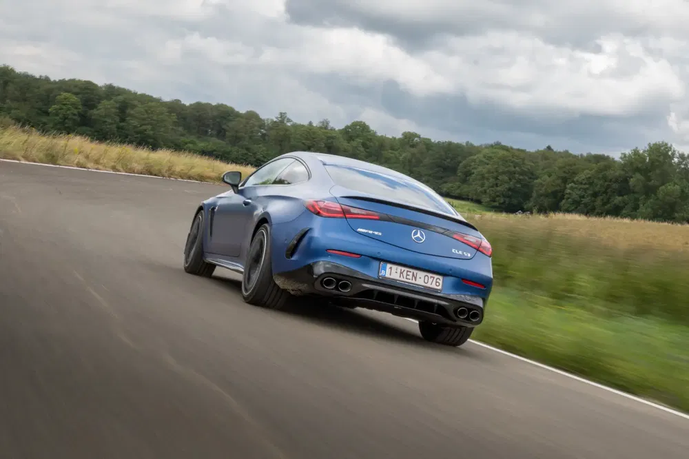 Mercedes-Benz CLS bleu roulant sur route sinueuse par temps nuageux.