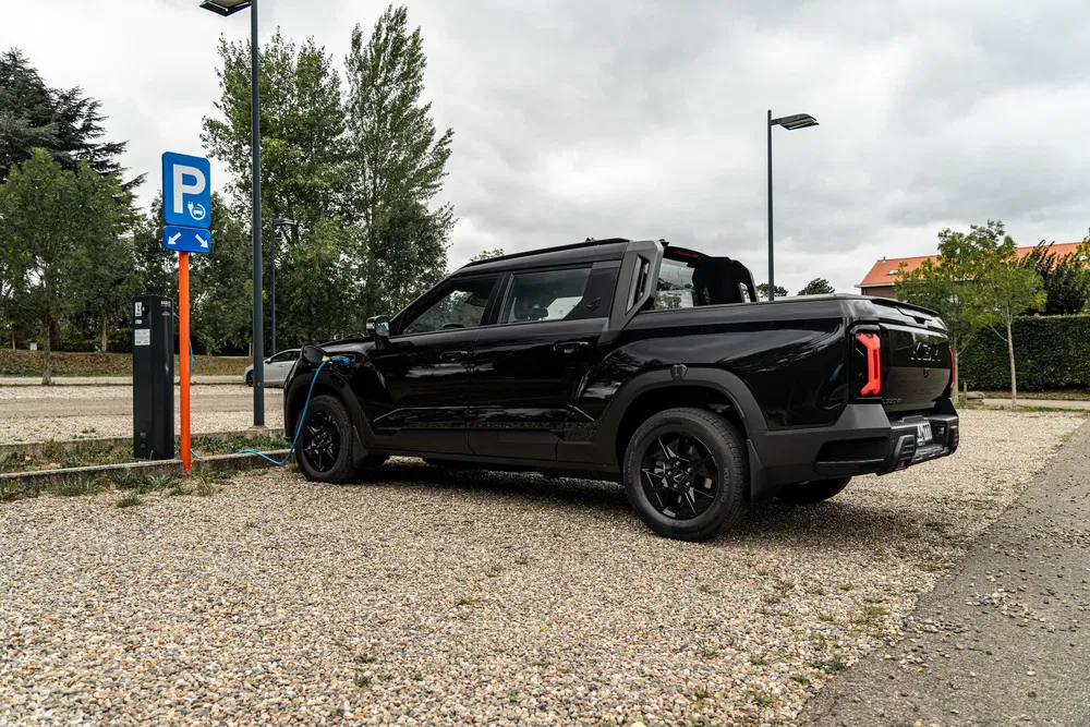 Camionnette électrique SsangYong Musso noire en charge à une borne publique.