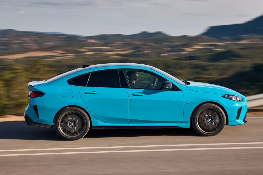 BMW Série 2 Gran Coupé bleu sur route montagneuse, profil latéral dynamique.