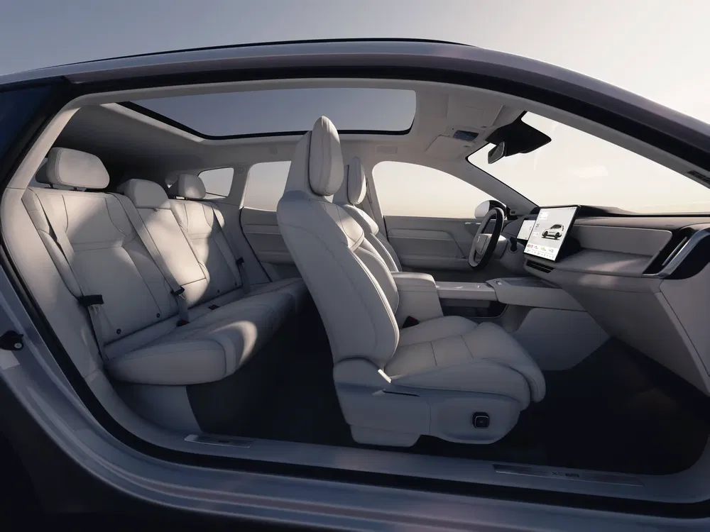 Intérieur spacieux et moderne d'une voiture électrique Volvo avec sièges en cuir blanc et écran tactile.