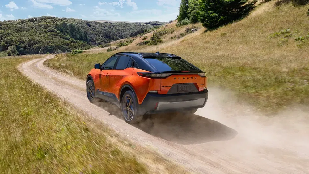 {"fr":"Subaru électrique SUV orange sur chemin de terre en pleine campagne verdoyante.","nl":"Oranje elektrische Subaru SUV op een stoffige landweg in een groene omgeving."}