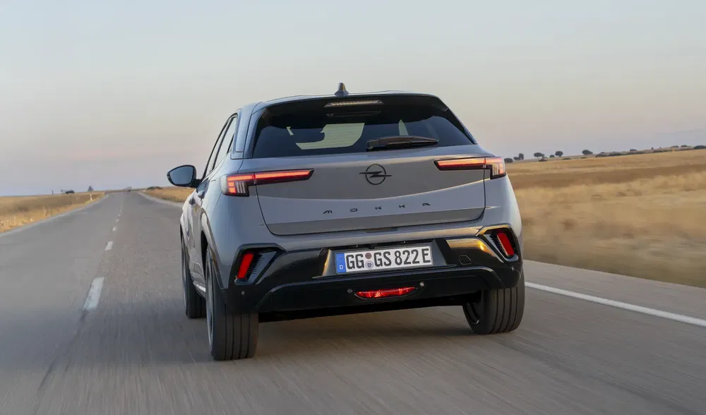 Elektrische Opel Mokka rijdt op een open weg bij zonsondergang.