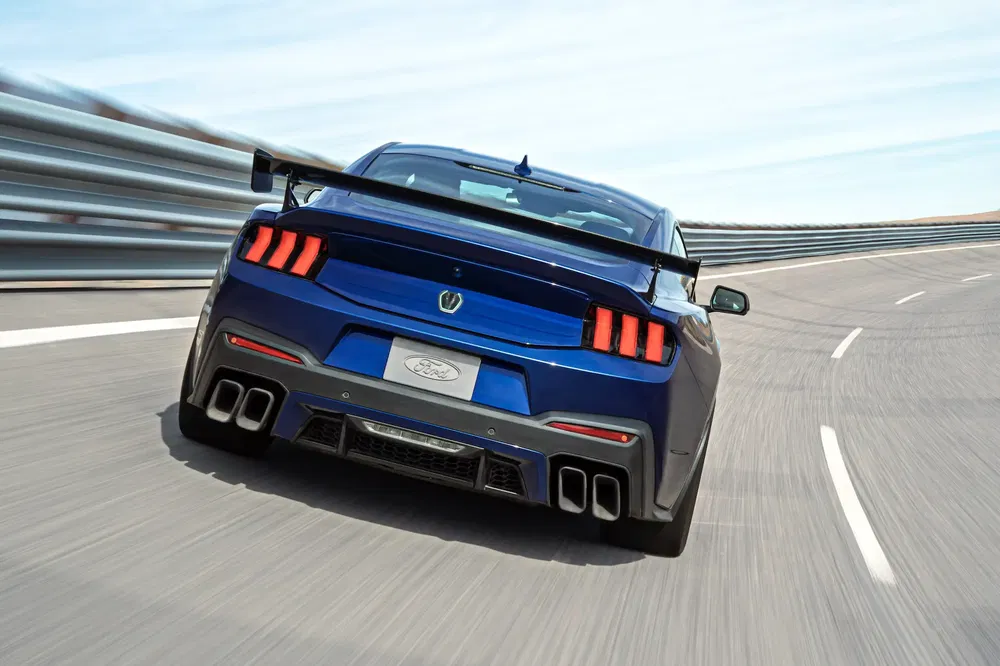 Ford Mustang bleu en virage serré sur circuit de course.