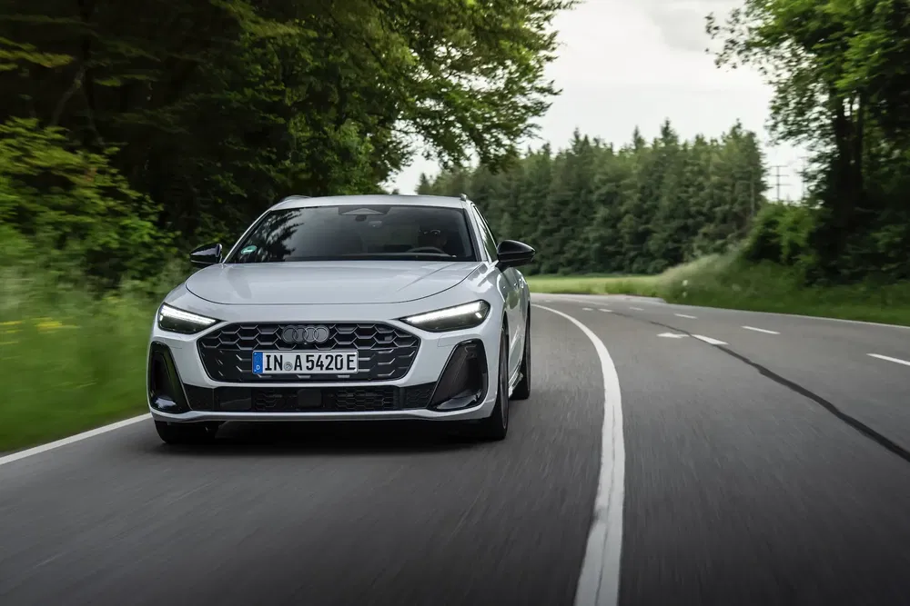 Elektrische Audi A3 rijdt op een met bomen omzoomde landelijke weg tijdens een test.