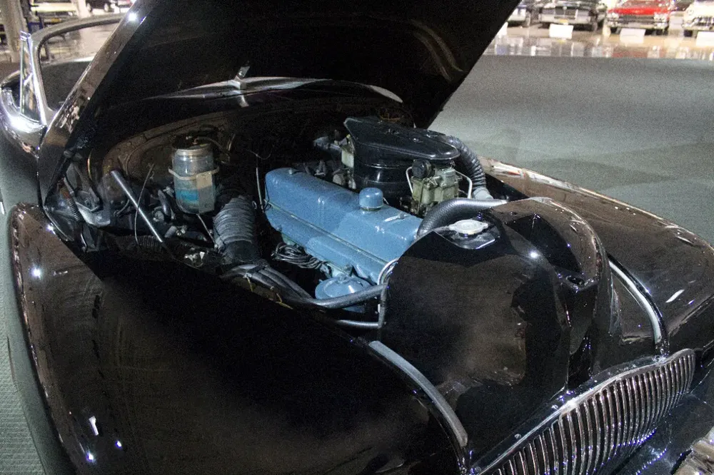 Moteur classique exposé sous le capot ouvert d'une voiture ancienne noire.