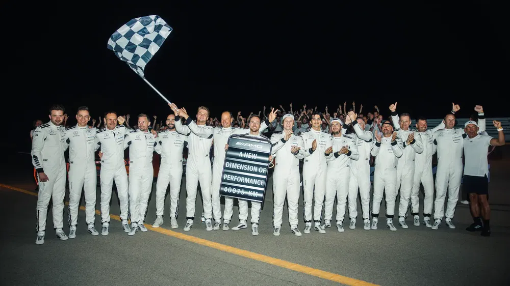 Équipe Porsche célèbre, tenue blanche, drapeau à damier, performance nocturne spectaculaire.