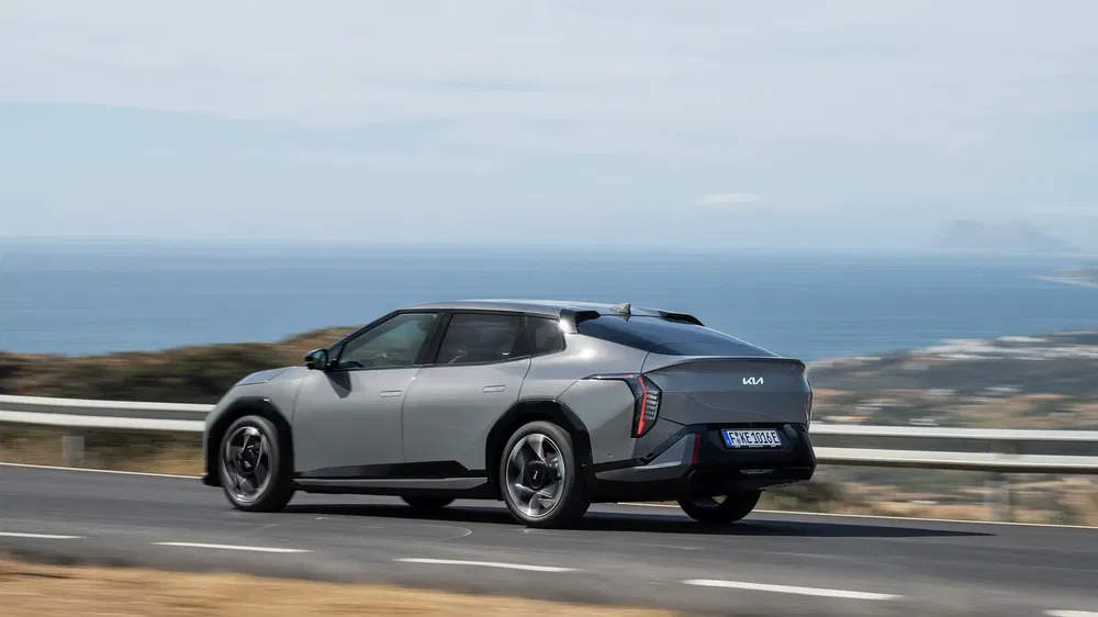 Kia EV6 grijs langs kustweg met uitzicht op zee, aerodynamisch ontwerp.