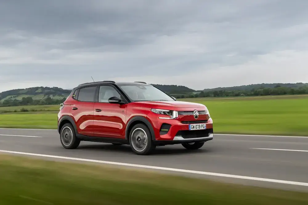SUV Citroën C3 Aircross rouge roulant sur une route de campagne verdoyante.