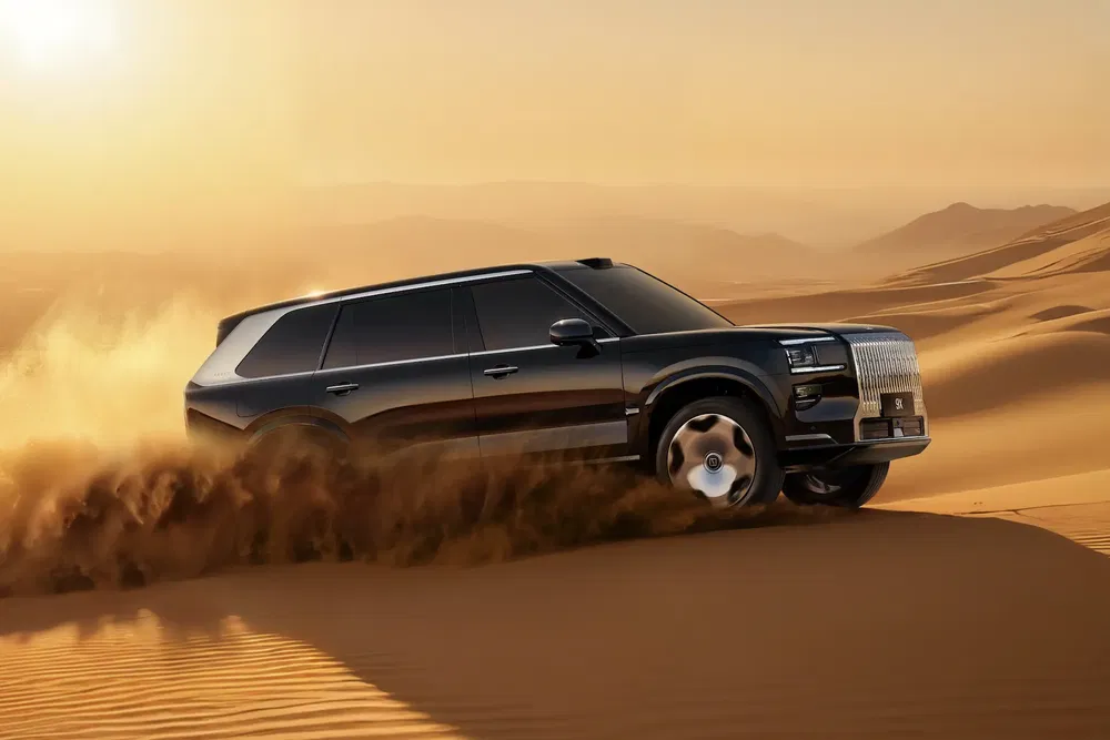 SUV roulant dans le désert, soulevant un nuage de sable sous un ciel dégagé.