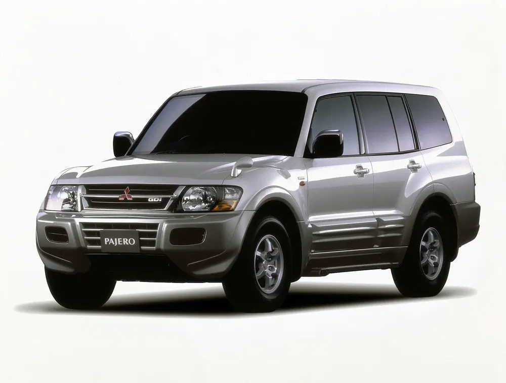 Zilveren Mitsubishi Pajero SUV van opzij, robuust en stijlvol ontwerp.