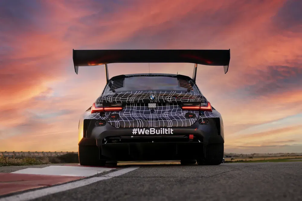 {"fr":"BMW racing car avec aileron large sur circuit au coucher du soleil.","nl":"BMW-raceauto met grote spoiler op circuit bij zonsondergang."}