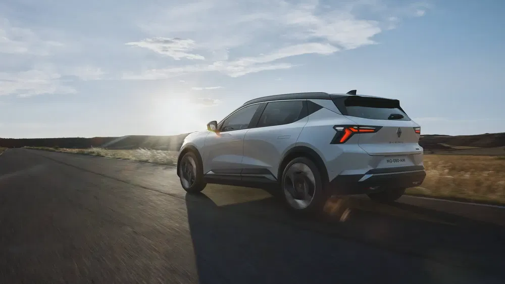 SUV Renault Austral roulant sur une route au coucher du soleil.
