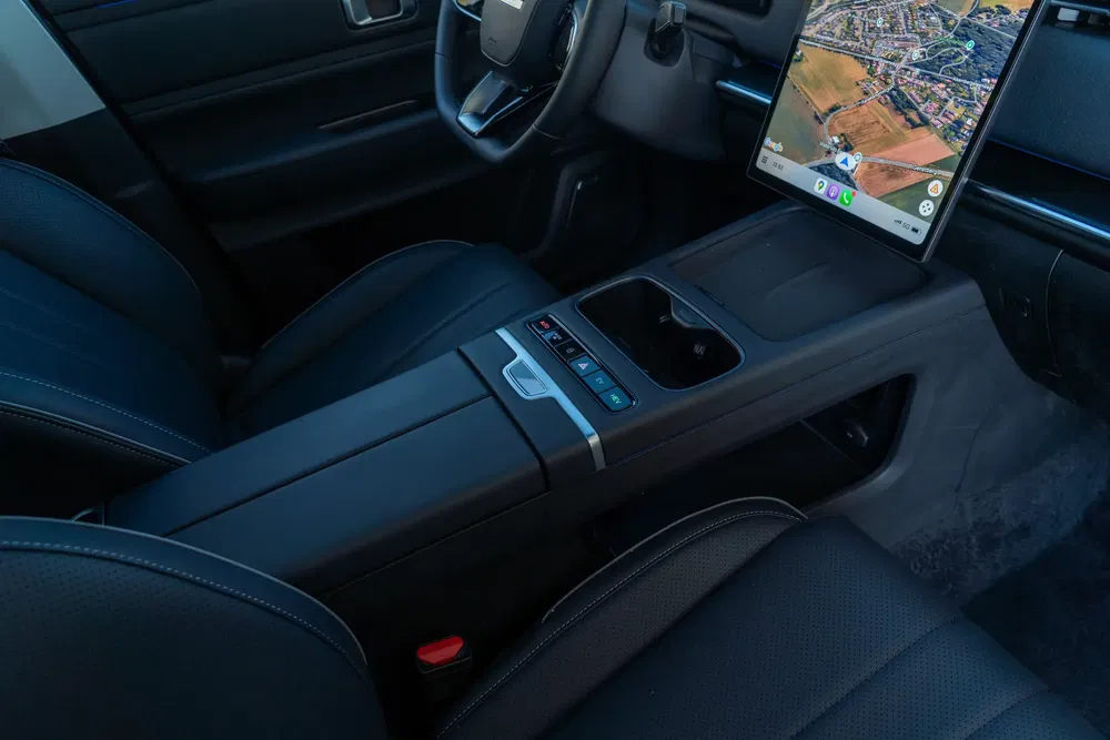 Modern interieur van een Tesla-auto met touchscreen en zwarte lederen stoelen.