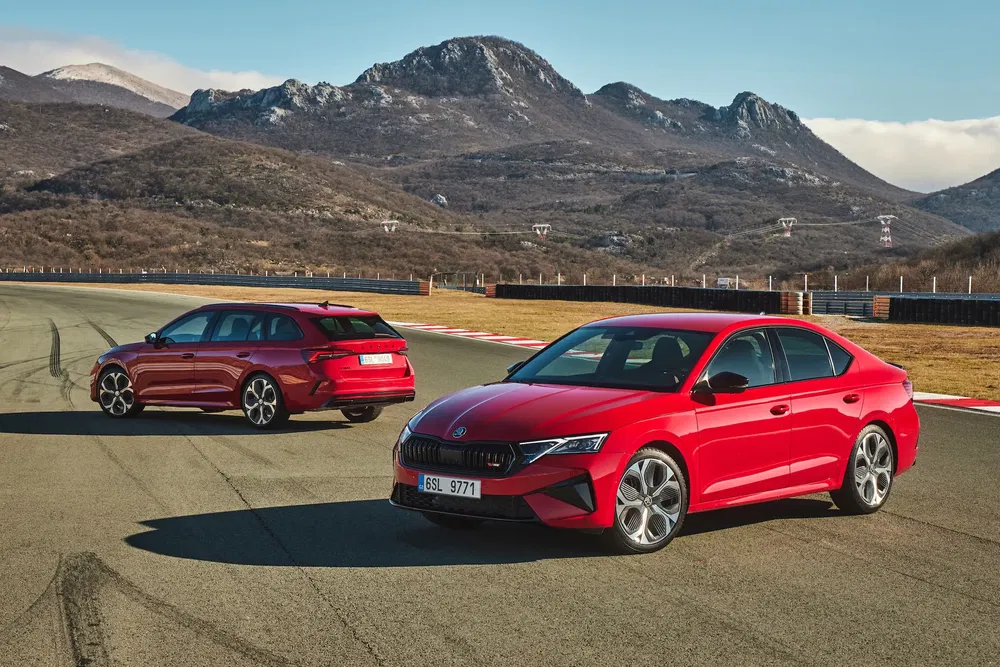 Deux Skoda rouges sur circuit, entourées de montagnes, parfait pour essais de performances.