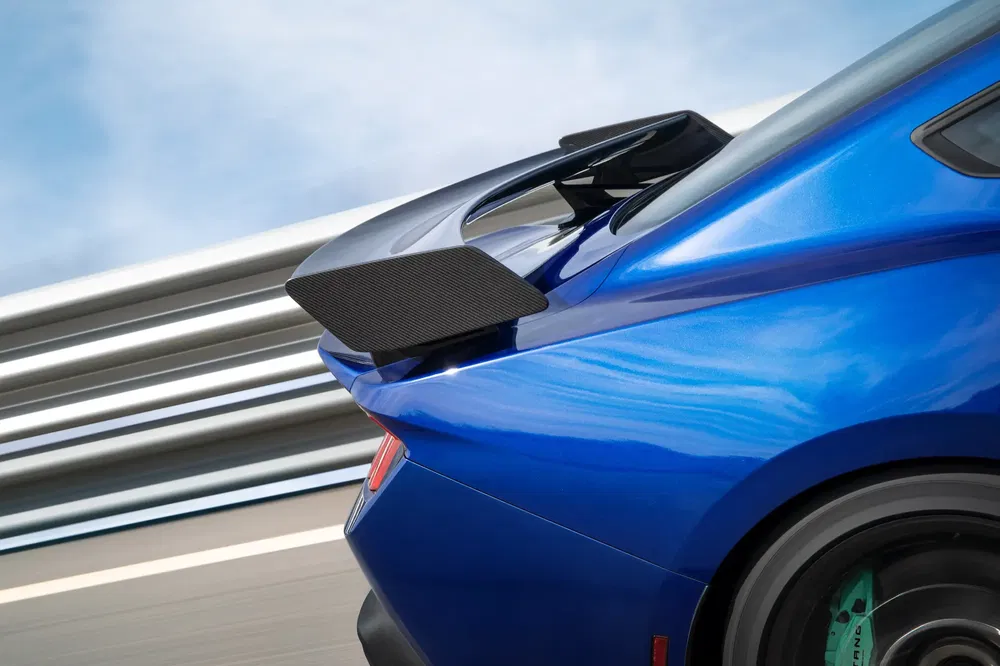 Arrière d'une voiture bleue sportive avec aileron aérodynamique en carbone au design futuriste.