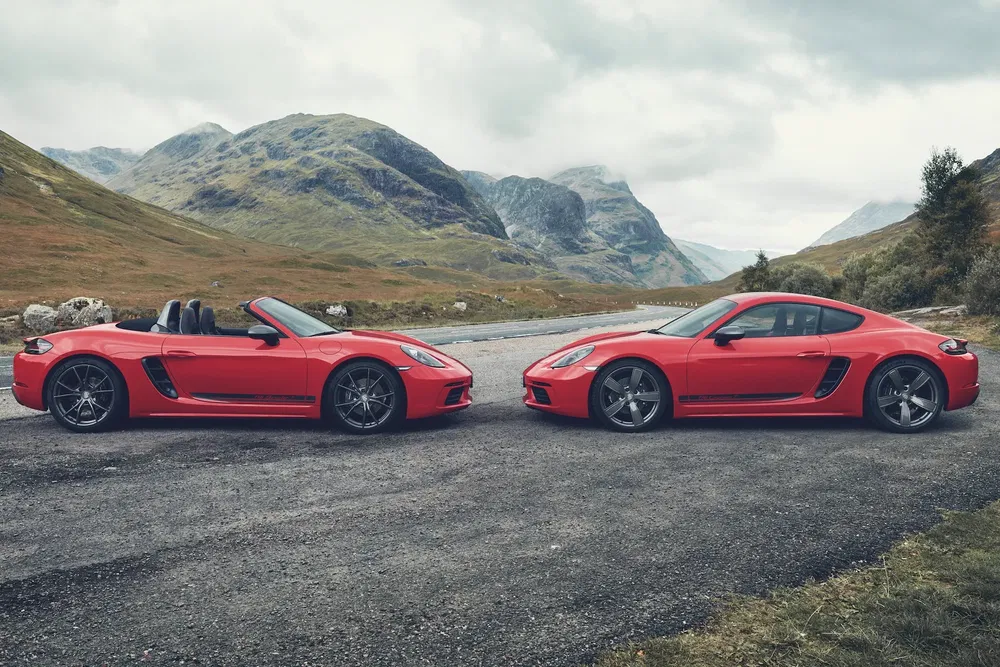 Deux Porsche rouges sur une route sinueuse de montagne panoramique.