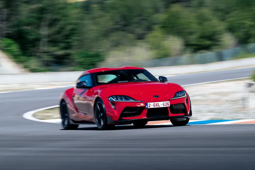 Rode Toyota Supra draait met hoge prestaties op bochtig circuit.