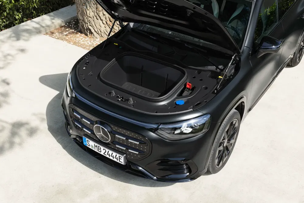 Open motorkap van een elektrische Mercedes met ruime frunk in zonlicht.