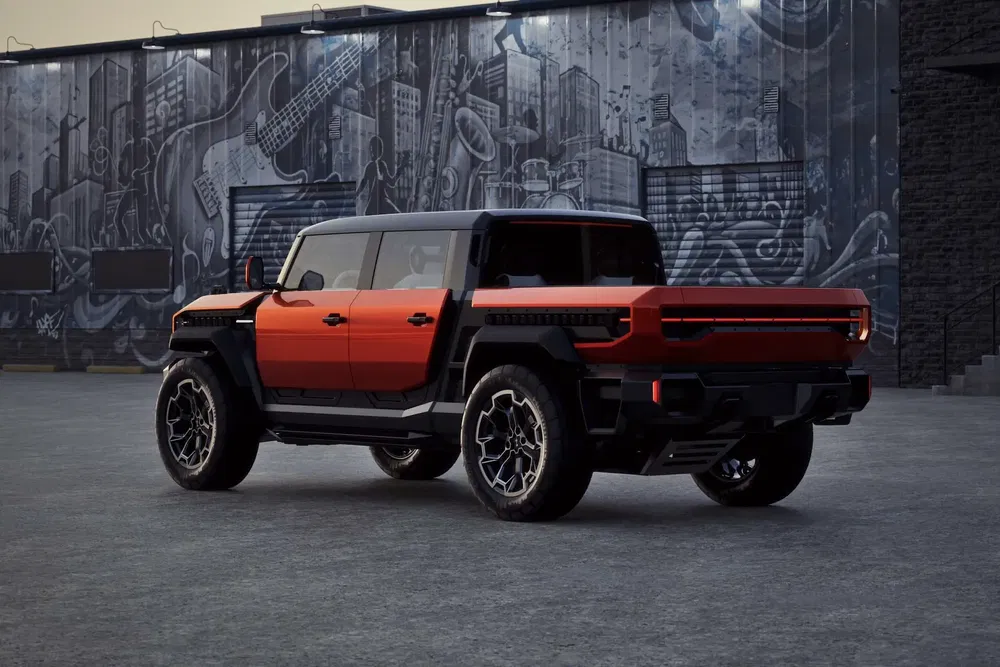 GMC Hummer EV rouge stationné devant une fresque urbaine en noir et blanc.