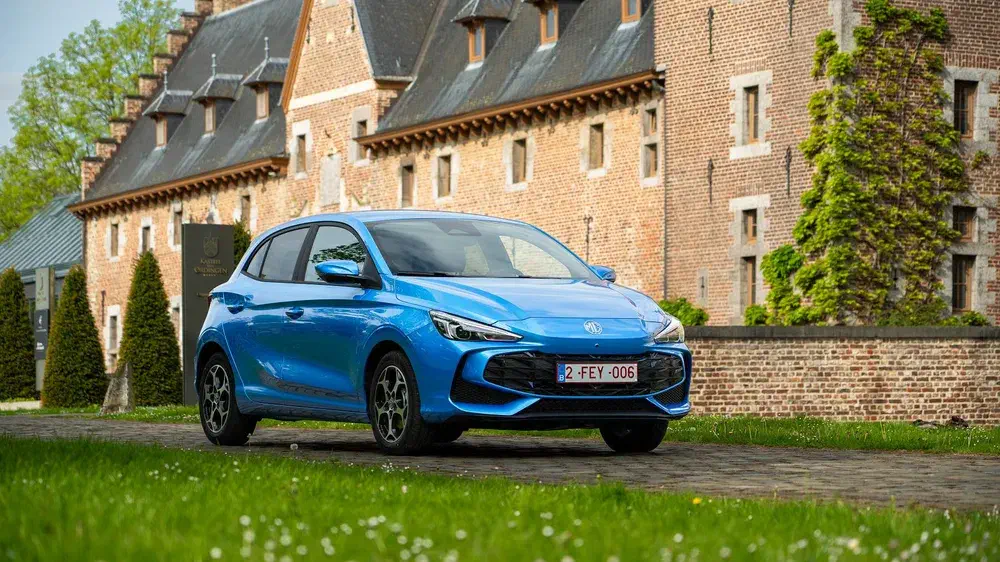Blauwe elektrische MG 4 voor historisch gebouw in landelijke omgeving.