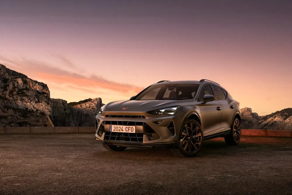 SUV Cupra Tavascan 2024 sur fond de coucher de soleil montagneux.