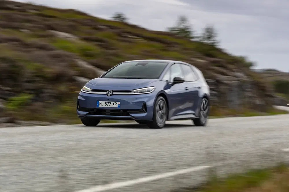 Volkswagen ID.3 blauw rijdt op kronkelige weg, natuurlijke achtergrond.