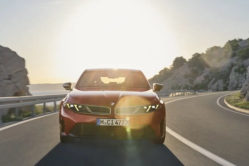 BMW roux roulant sur route sinueuse au coucher du soleil.