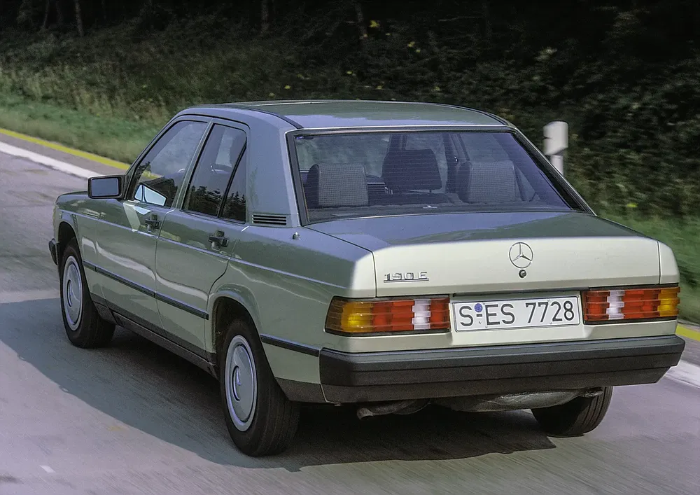 Voiture classique Mercedes-Benz 190E argent sur route, design intemporel et élégant.