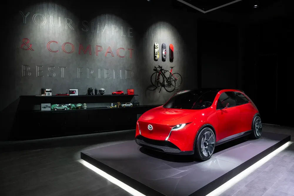 Rode Mazda compacte in moderne showroom, subtiele verlichting en minimalistische muurdecoratie.