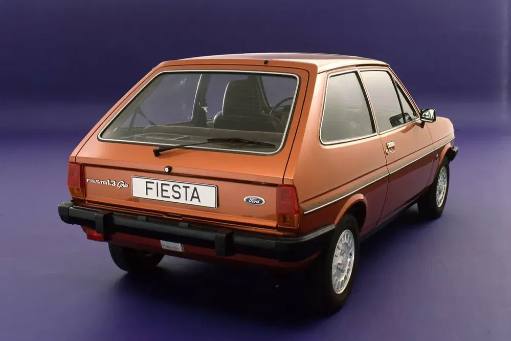Vue arrière d'une Ford Fiesta 1.3 Ghia marron, fond violet, années 1980.