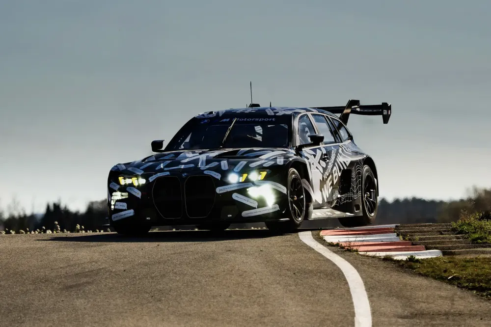 Elektrische BMW-prototype op circuit, camouflage-ontwerp, LED-koplampen, grote achtervleugel.