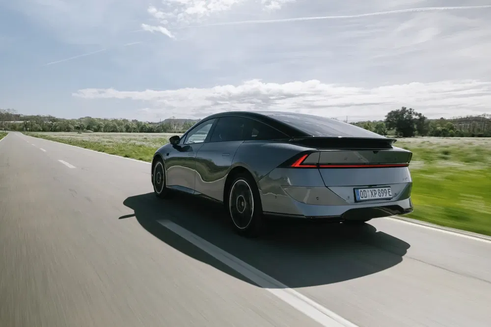 Voiture électrique Peugeot 408 grise roulant sur une route en campagne, ciel dégagé.