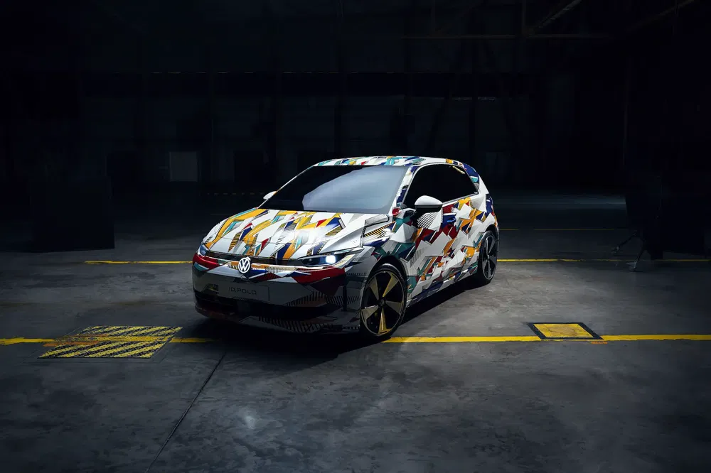 Volkswagen recouverte de motifs géométriques colorés dans un garage sombre.