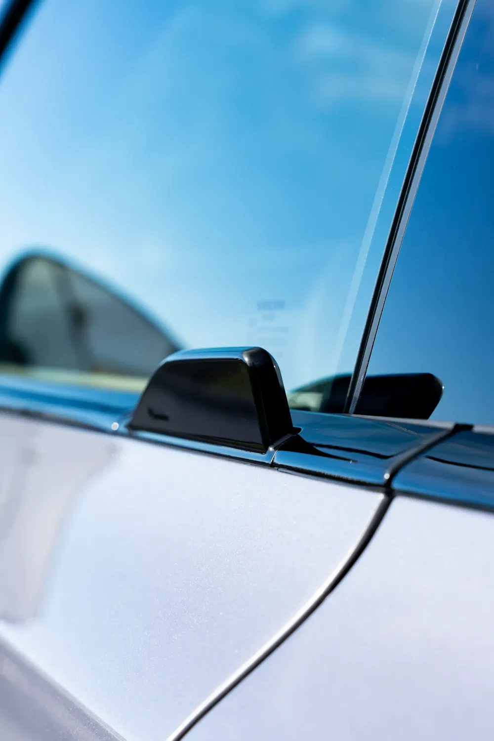 Antenne requin noire sur le toit d'une voiture moderne, ciel bleu en arrière-plan.