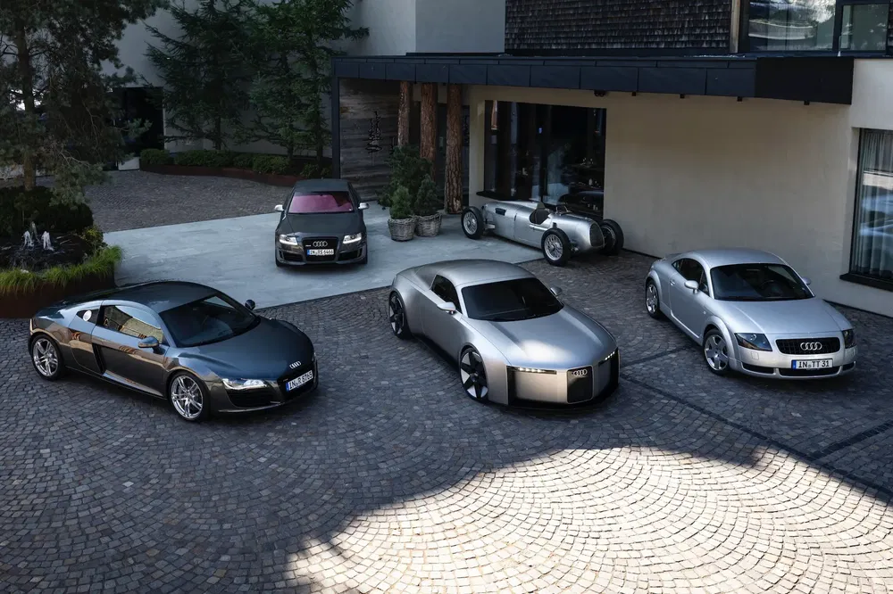Collection de modèles Audi, y compris R8, classiques et concepts, garés sur un pavé.
