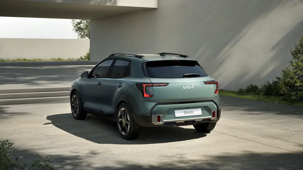 Groene Kia Stonic SUV in moderne oprit, schaduwen op betonnen vloer.