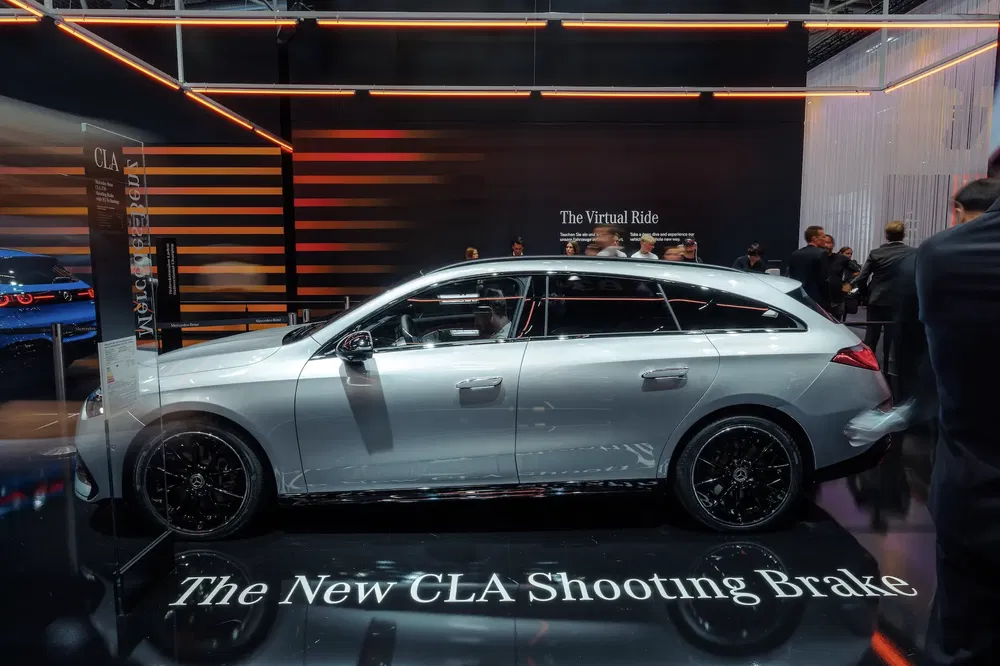 {"fr":"Mercedes CLA Shooting Brake argent, exposition auto moderne, éclairage orange interne.","nl":"Mercedes CLA Shooting Brake zilver, moderne autoshow, oranje interieurverlichting."}