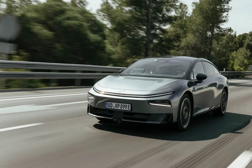 Voiture électrique Polestar 4 grise sur l'autoroute, entourée de forêt verte.