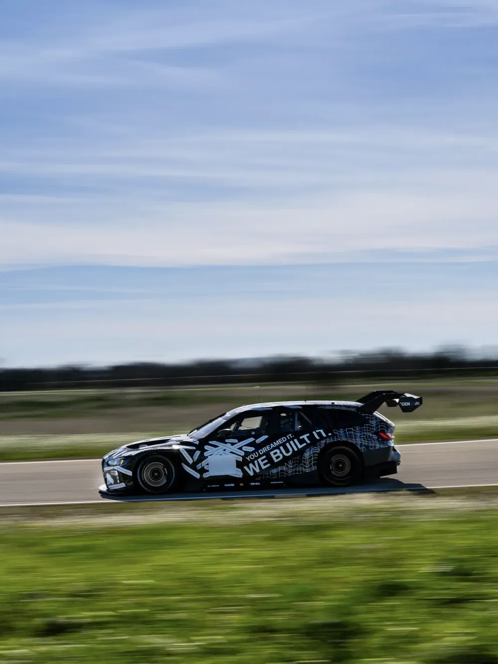 Snel racende auto met grote spoiler op een circuit.