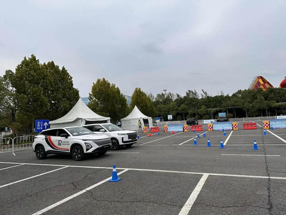 Essai routier avec deux voitures dans un parking avec cônes de signalisation bleus.