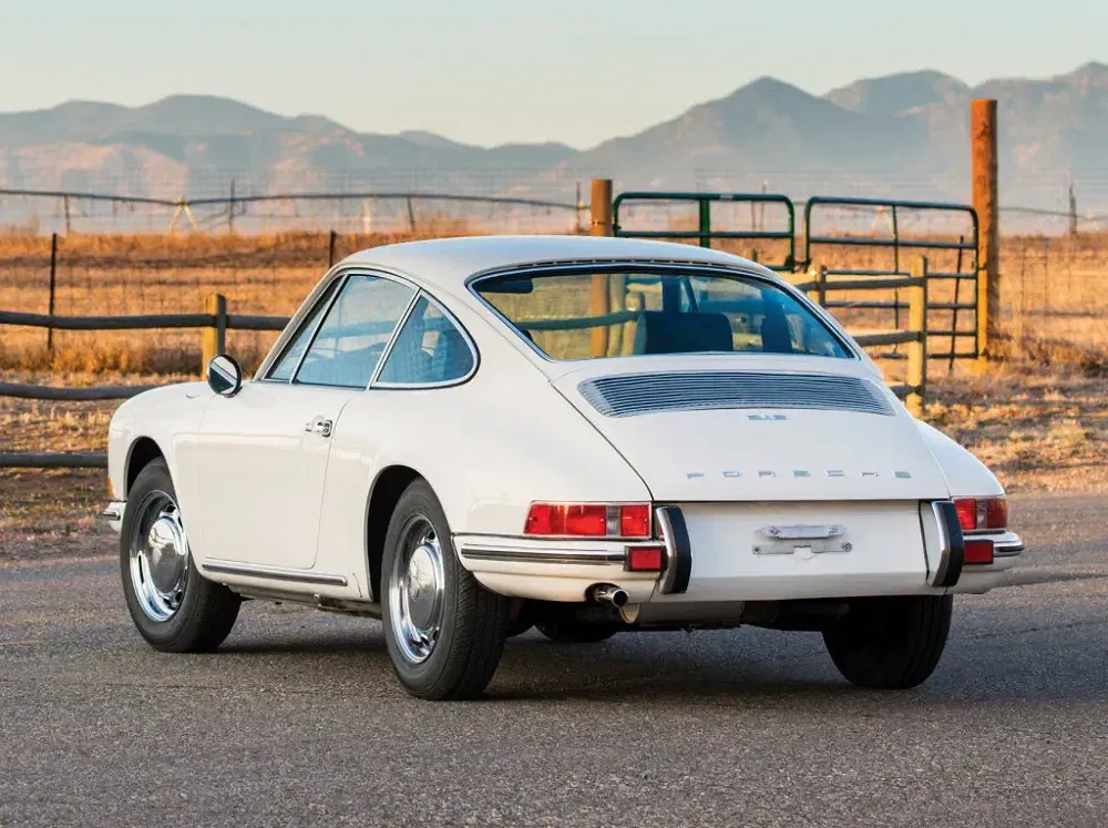 Porsche 912 blanche vintage, vue arrière, stationnée en plein air avec montagnes en arrière-plan.