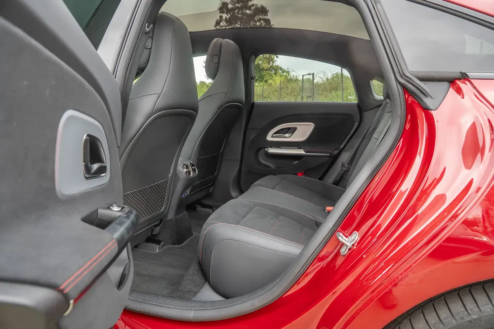 Intérieur d'une voiture rouge, sièges arrière en cuir noir avec accents rouges distinctifs.