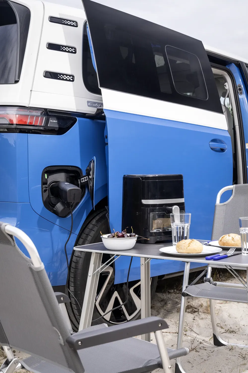 Van électrique Volkswagen ID.Buzz avec prise de charge, table de camping aménagée.