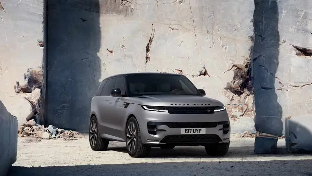 SUV Range Rover moderne stationné devant un mur de pierre imposant.