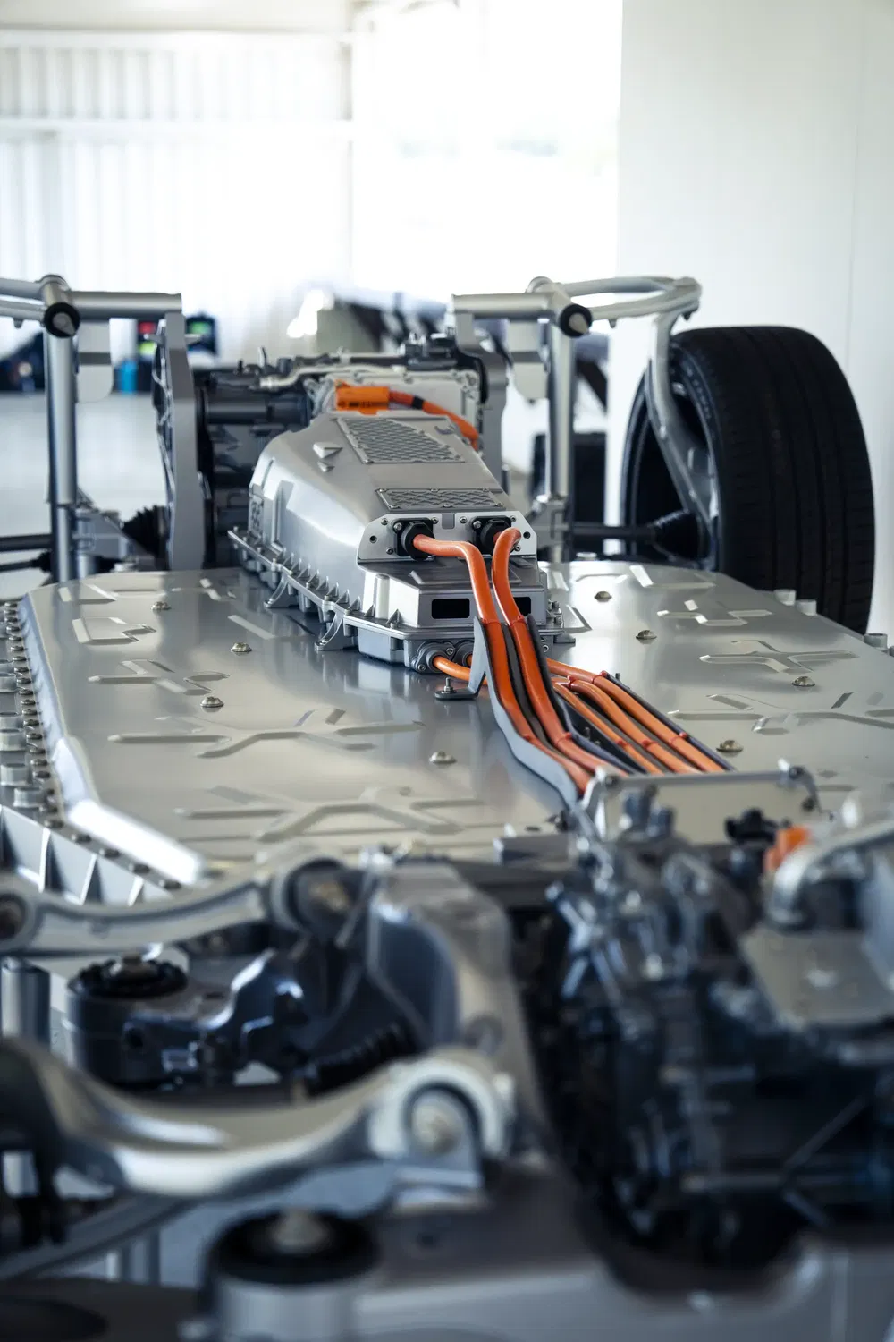 Châssis de voiture électrique avec câblage orange haute tension et structure métallique détaillée.
