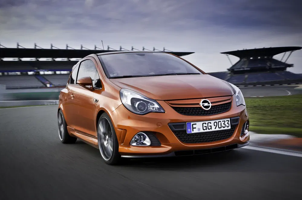 Opel Corsa orange sur circuit de course, voiture compacte performante en mouvement.